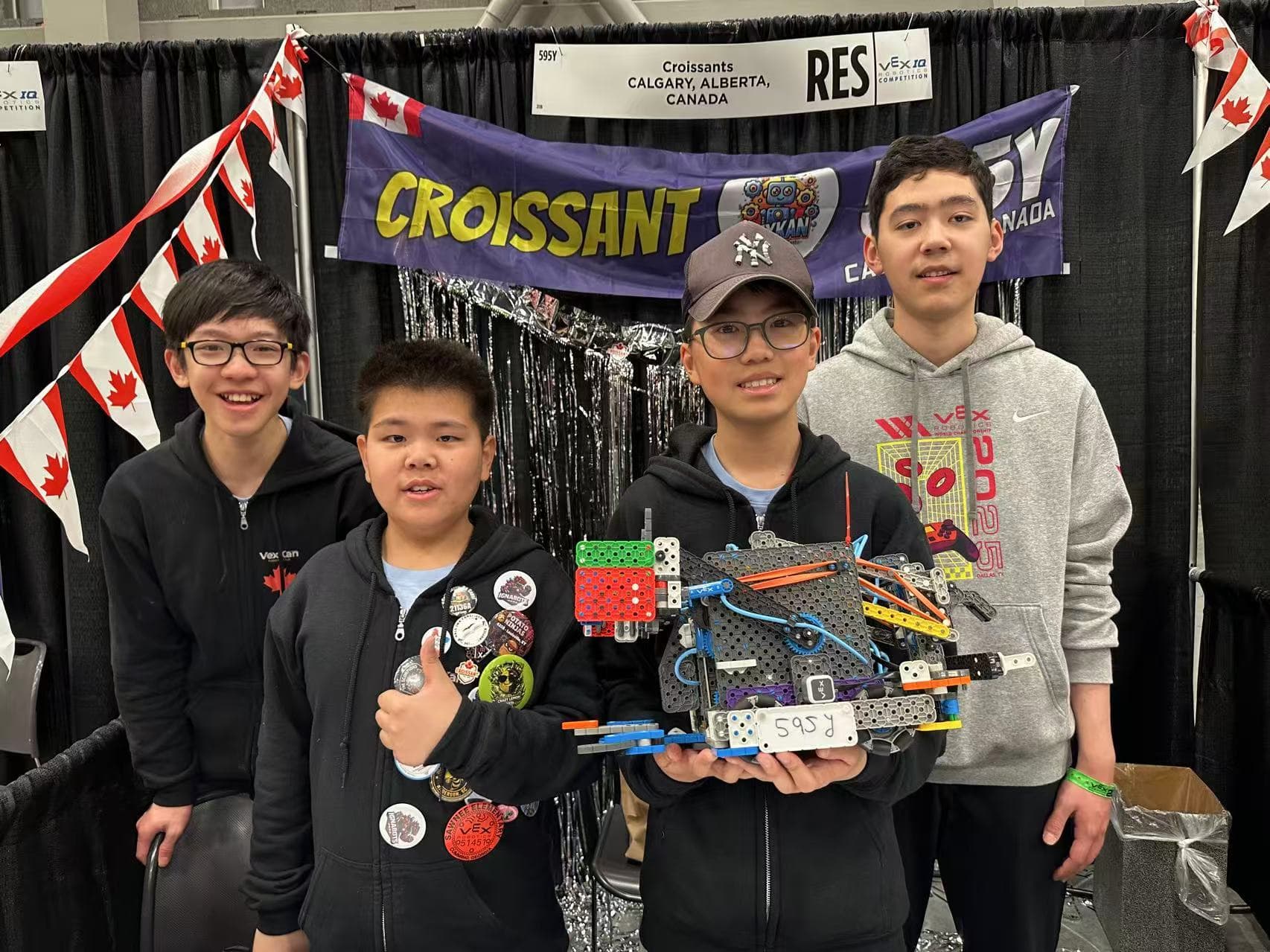Four clubbers at their pit holding up the VEX IQ robot they compete with.