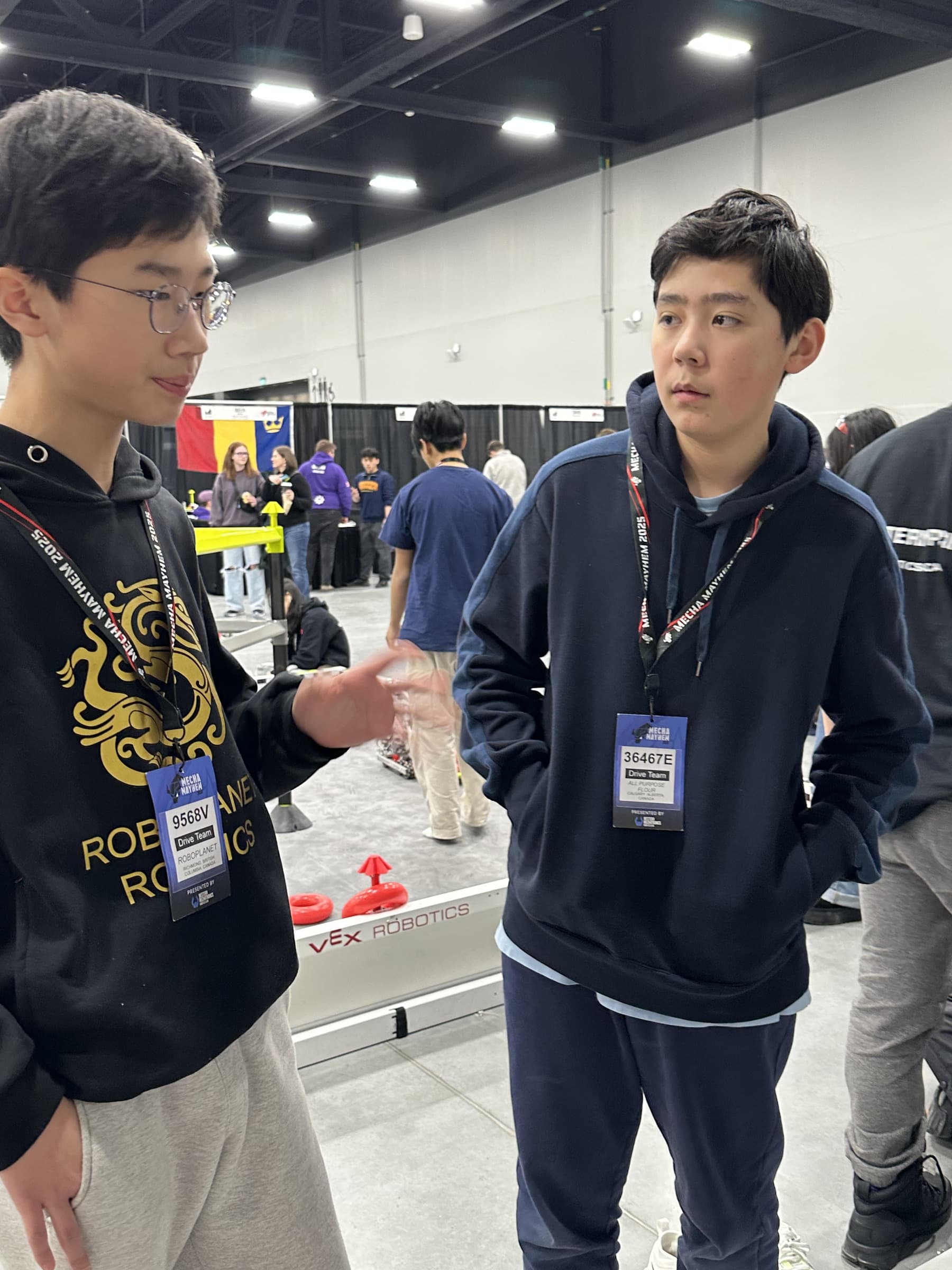 A clubber from 36467E talking with a driver from another club between matches, both wearing event lanyards, the field behind them.