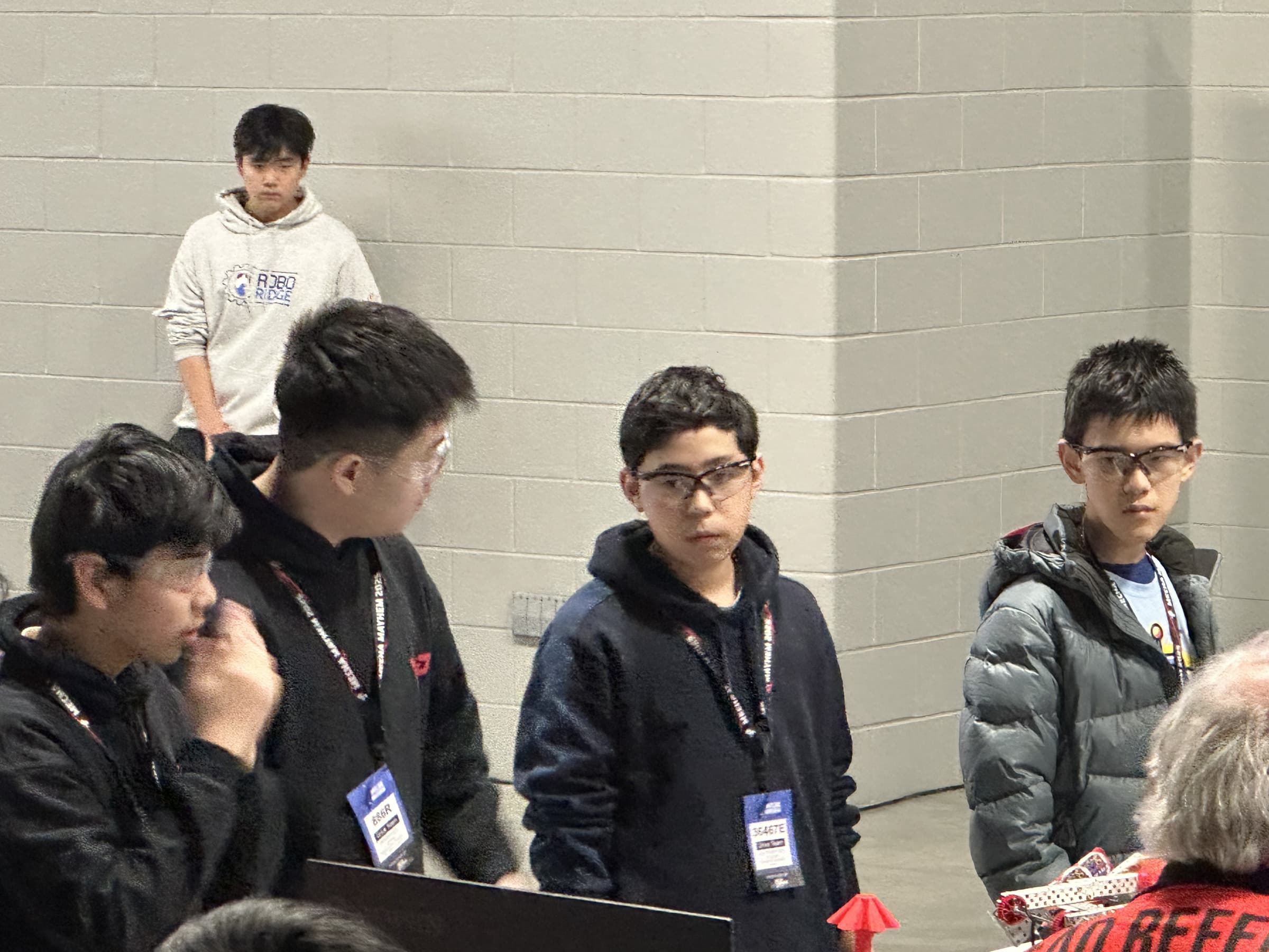 Drive teams from several clubs standing together in safety glasses, waiting for a match to be called.