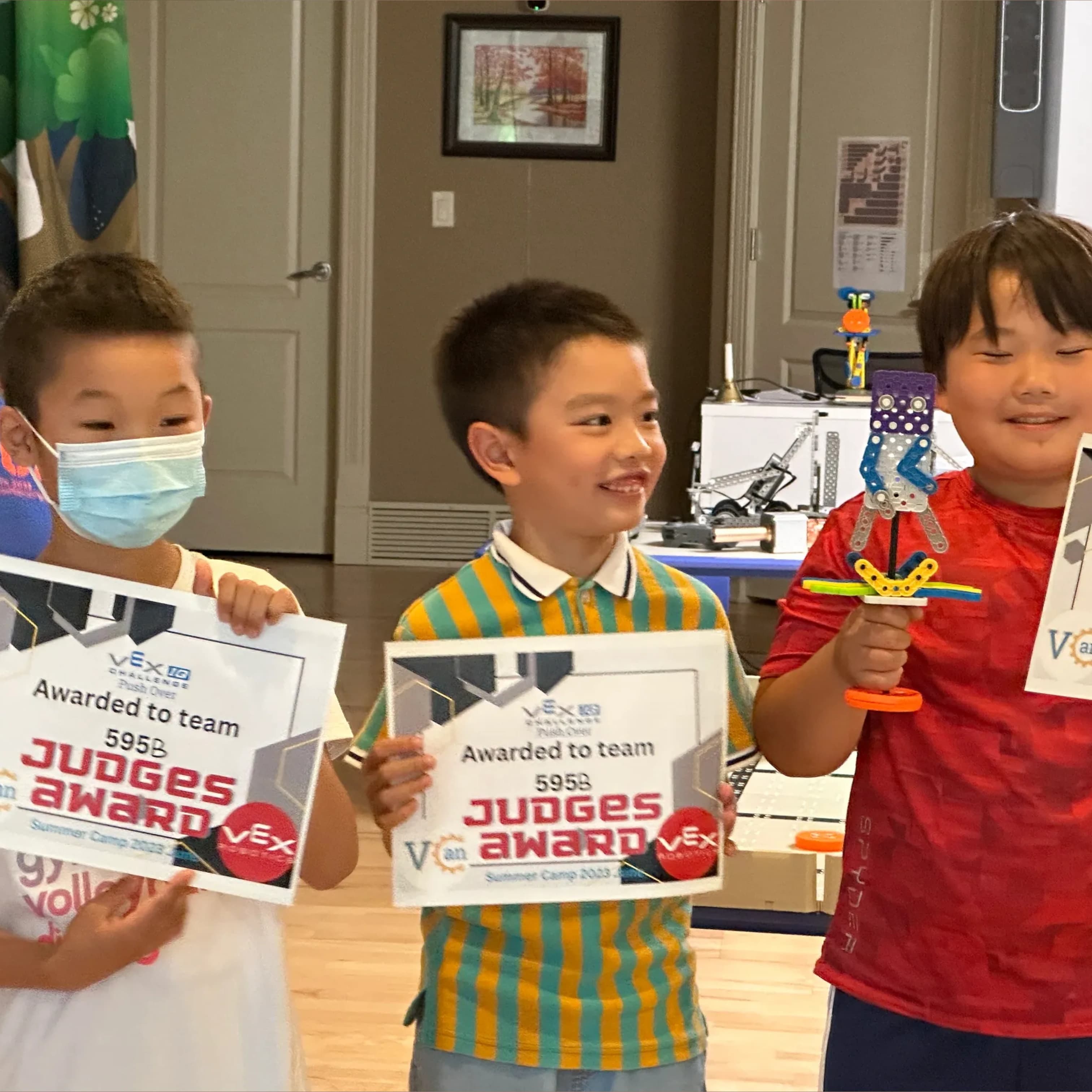 Three young clubbers holding up their certificates after a summer camp competition.