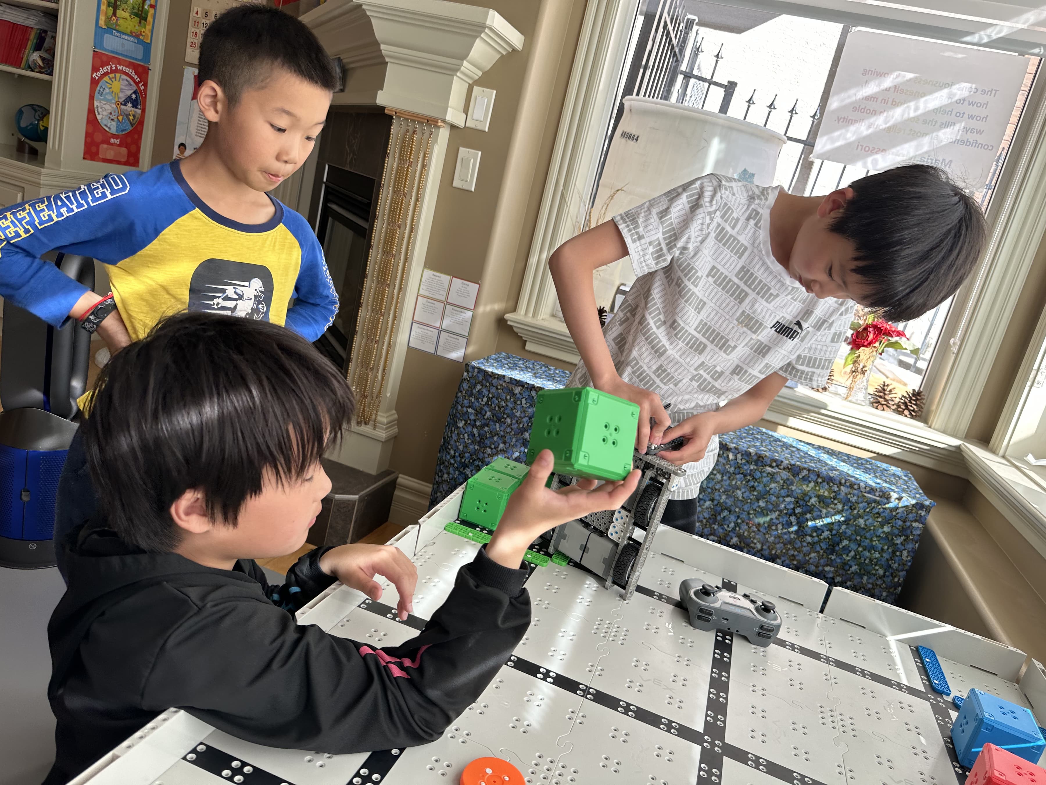 Two young clubbers at a VEX IQ field, one lowering a green robot onto the tiles while another works the controller.