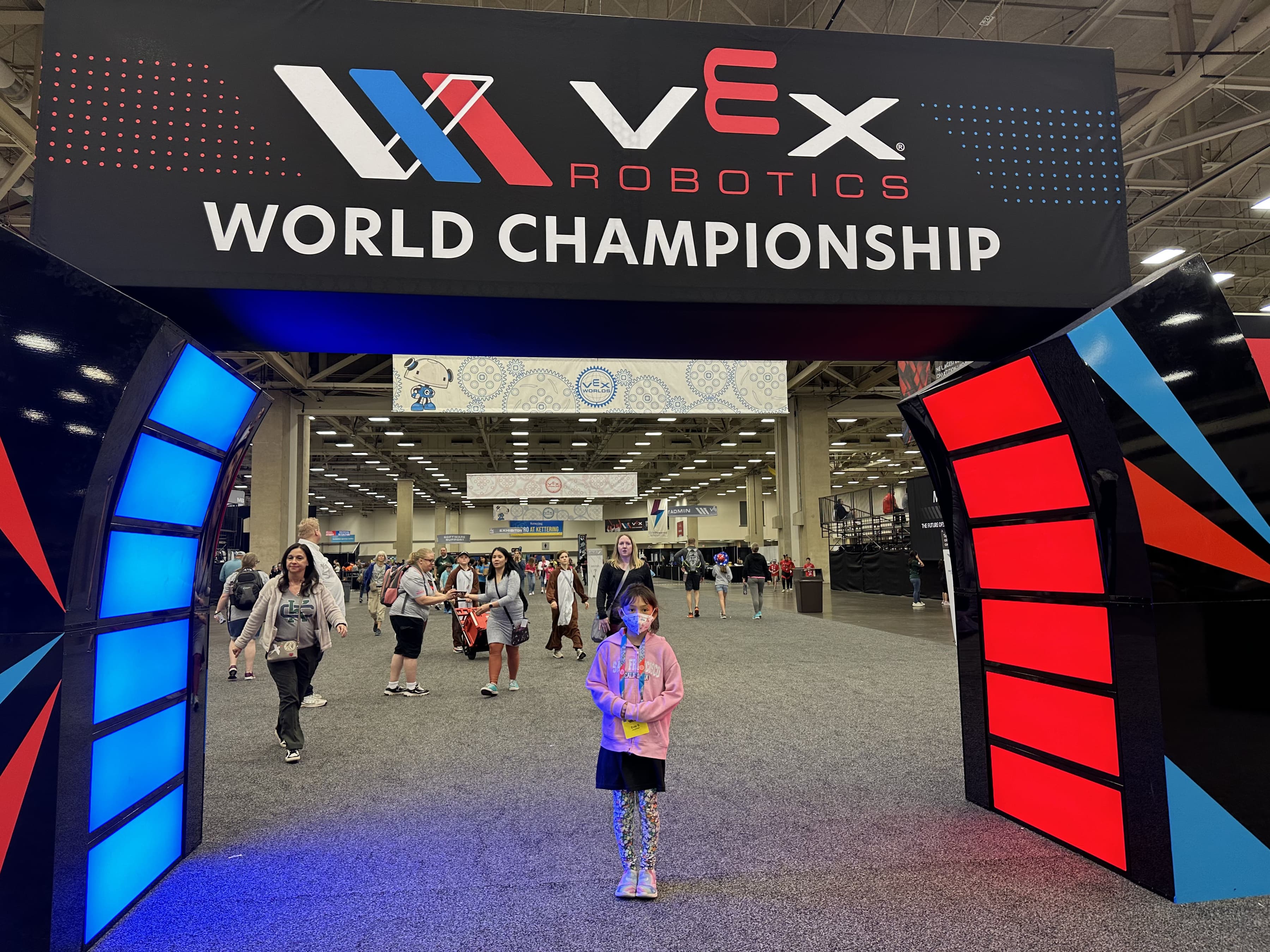The lit entrance arch to the VEX Robotics World Championship, with people walking through into the hall.