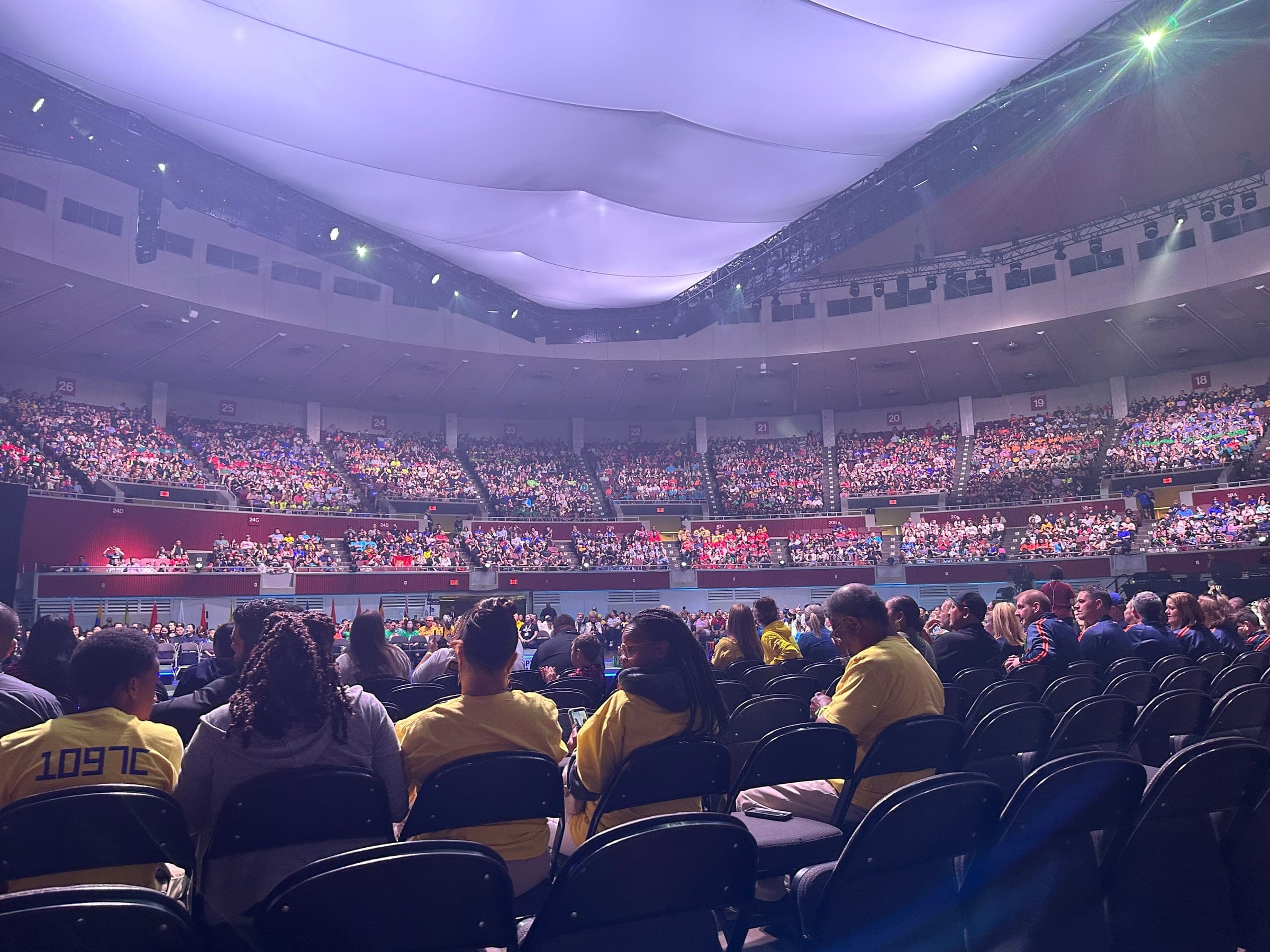 The arena at the World Championship seen from the floor seats, every tier filled with teams in their own colours.
