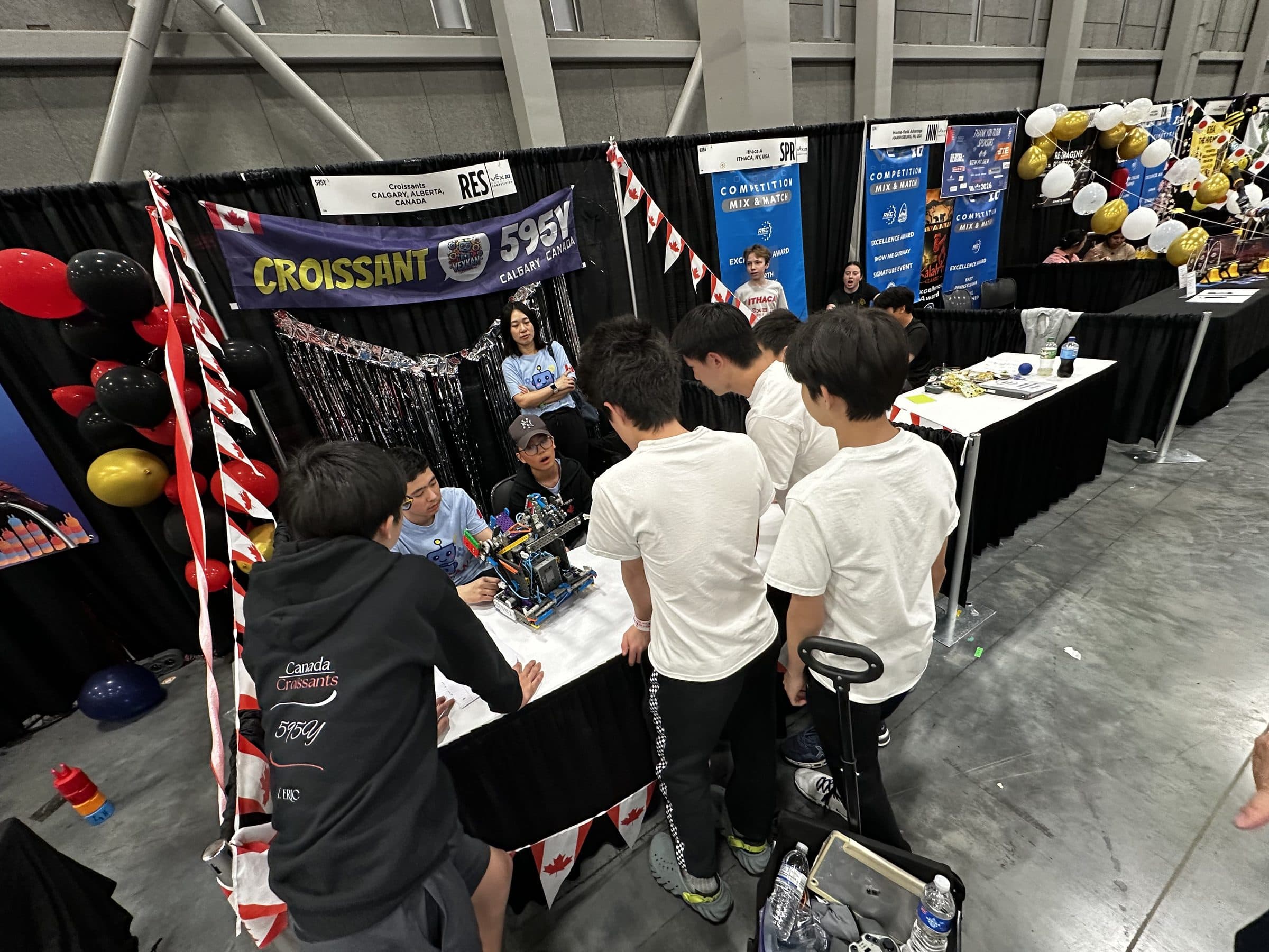 595Y's pit seen from above, Canadian flags and streamers strung across it and a queue of students from other teams crowded around the table to see the robot.