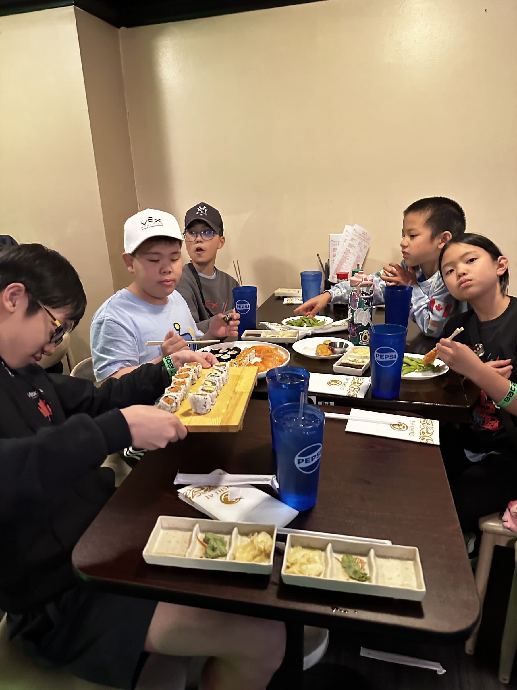 Six clubbers around a restaurant table sharing plates of sushi at the end of a competition day.